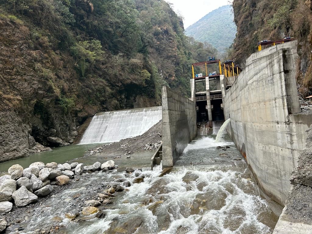 Super Madi hydropower headworks with concrete intake gates and water flowing through the river valley